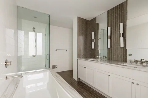 a spacious bathroom with a double vanity sink a large mirror a bathtub and shower