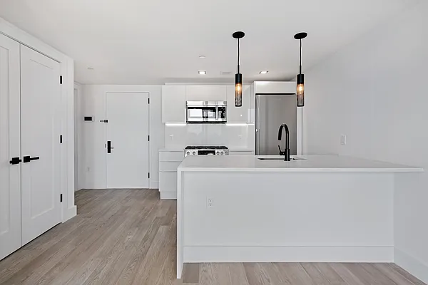1673 Ocean Avenue, Unit PH4 Brooklyn, NY 11230 - Photo 5 of 13 a kitchen with stainless steel appliances granite countertop a sink a refrigerator a stove and white cabinets with wooden floor