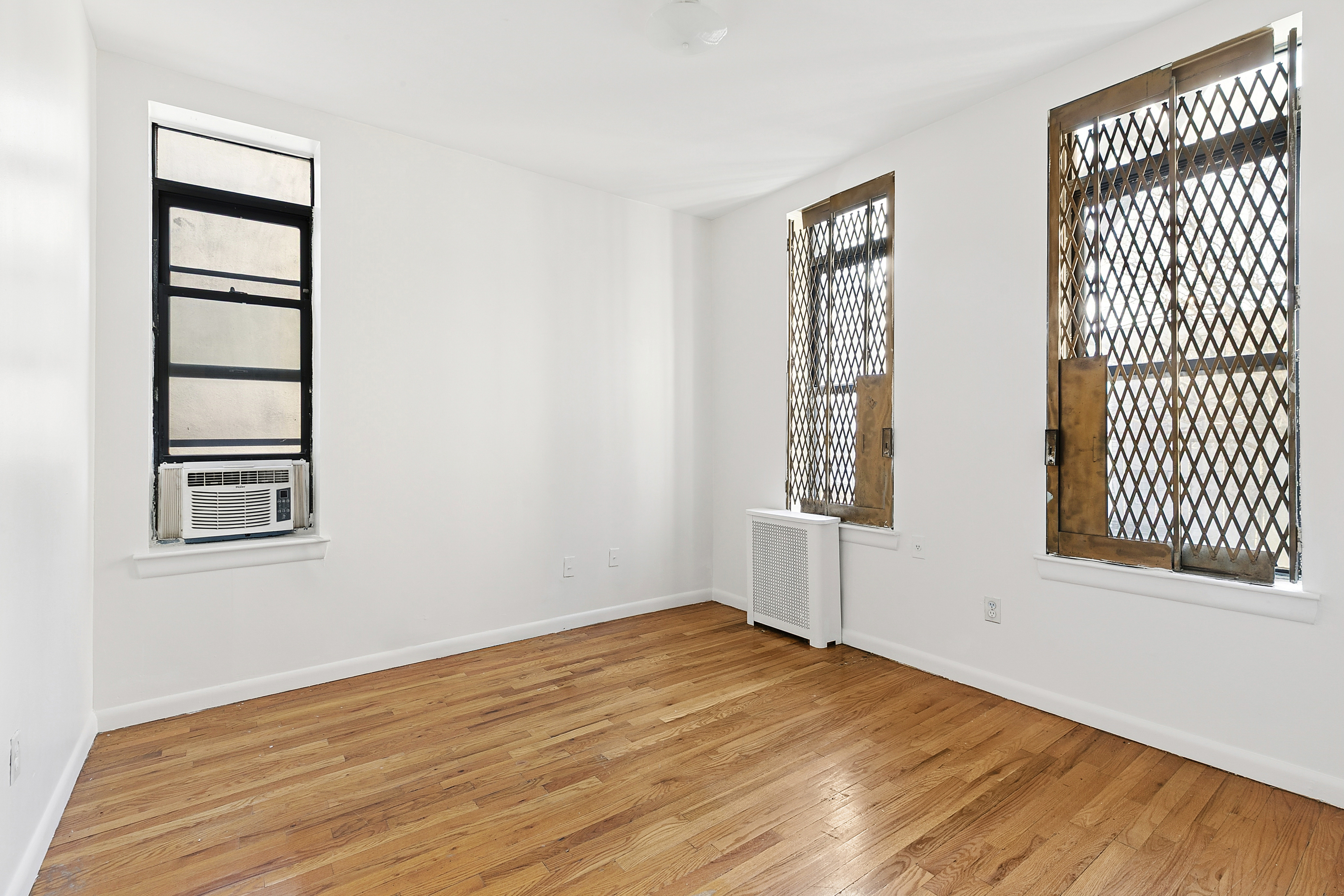 11 St Nicholas Avenue, Unit 5B Manhattan, NY 10026 - Photo 7 of 10 an empty room with wooden floor and windows