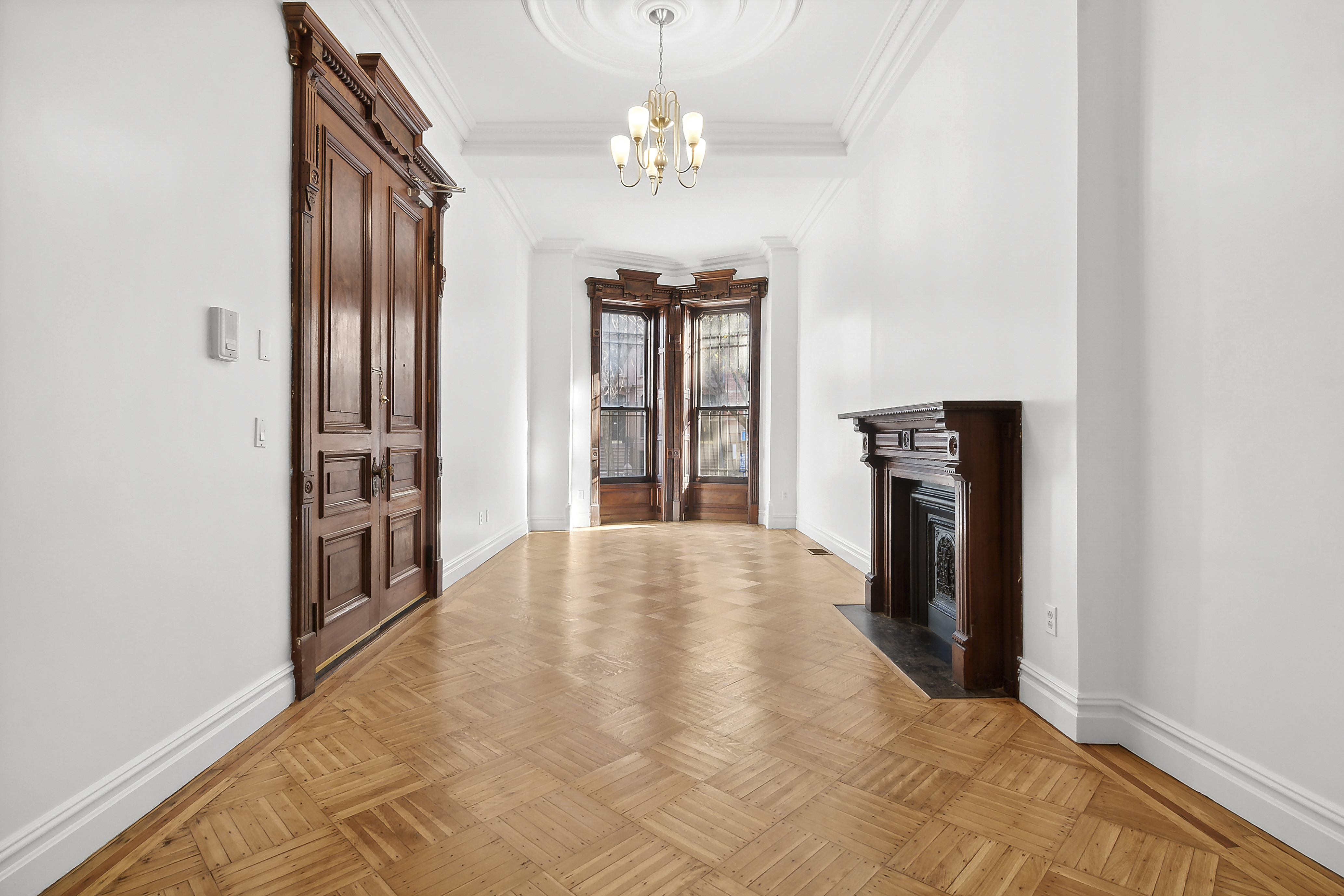 562 Washington Avenue, Unit 1 Brooklyn, NY 11238 - Photo 6 of 12 wooden floor in an empty room with a chandelier