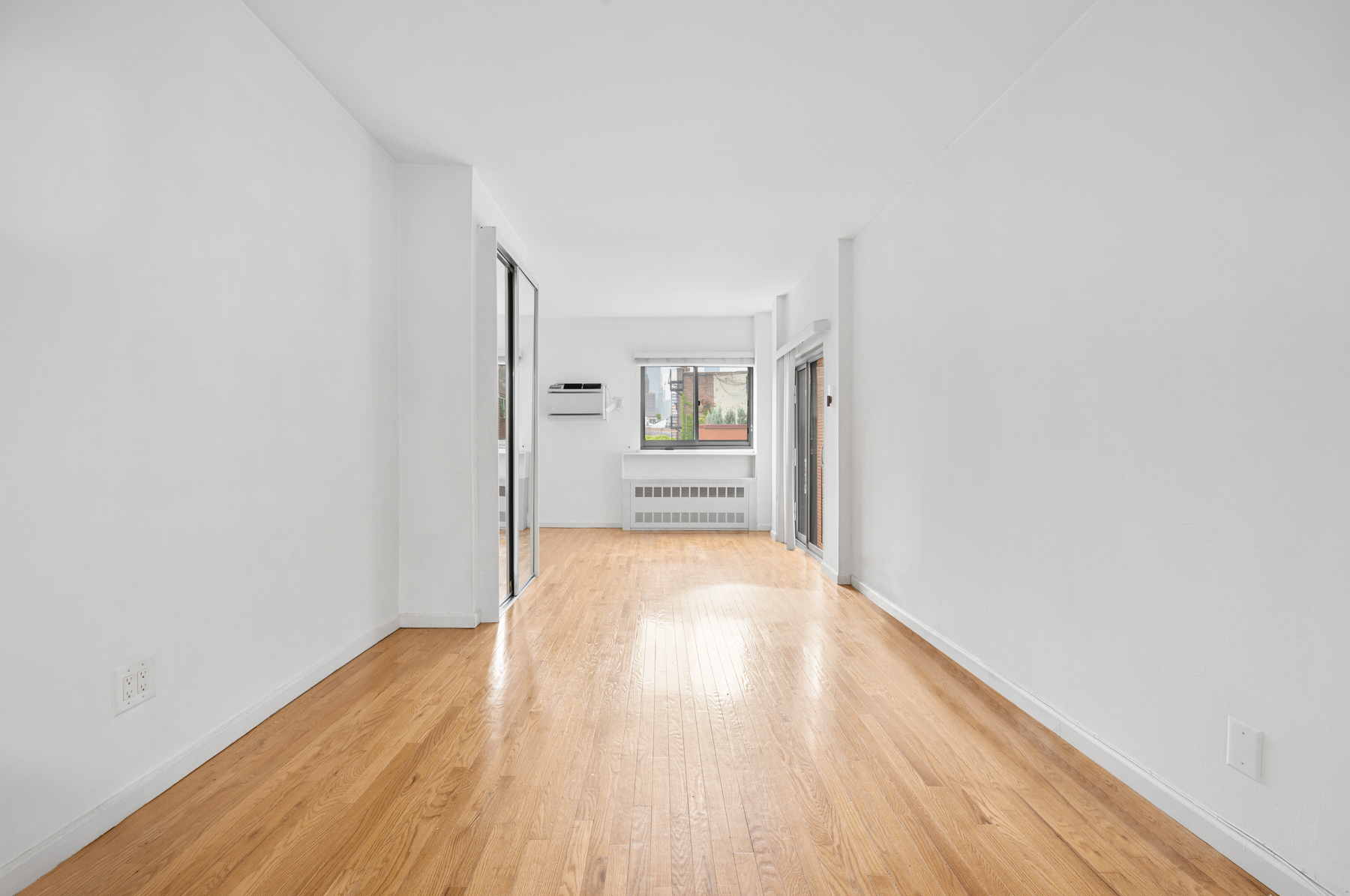 184 Thompson Street, Unit 4U Manhattan, NY 10012 - Photo 2 of 9 wooden floor in an empty room with a window