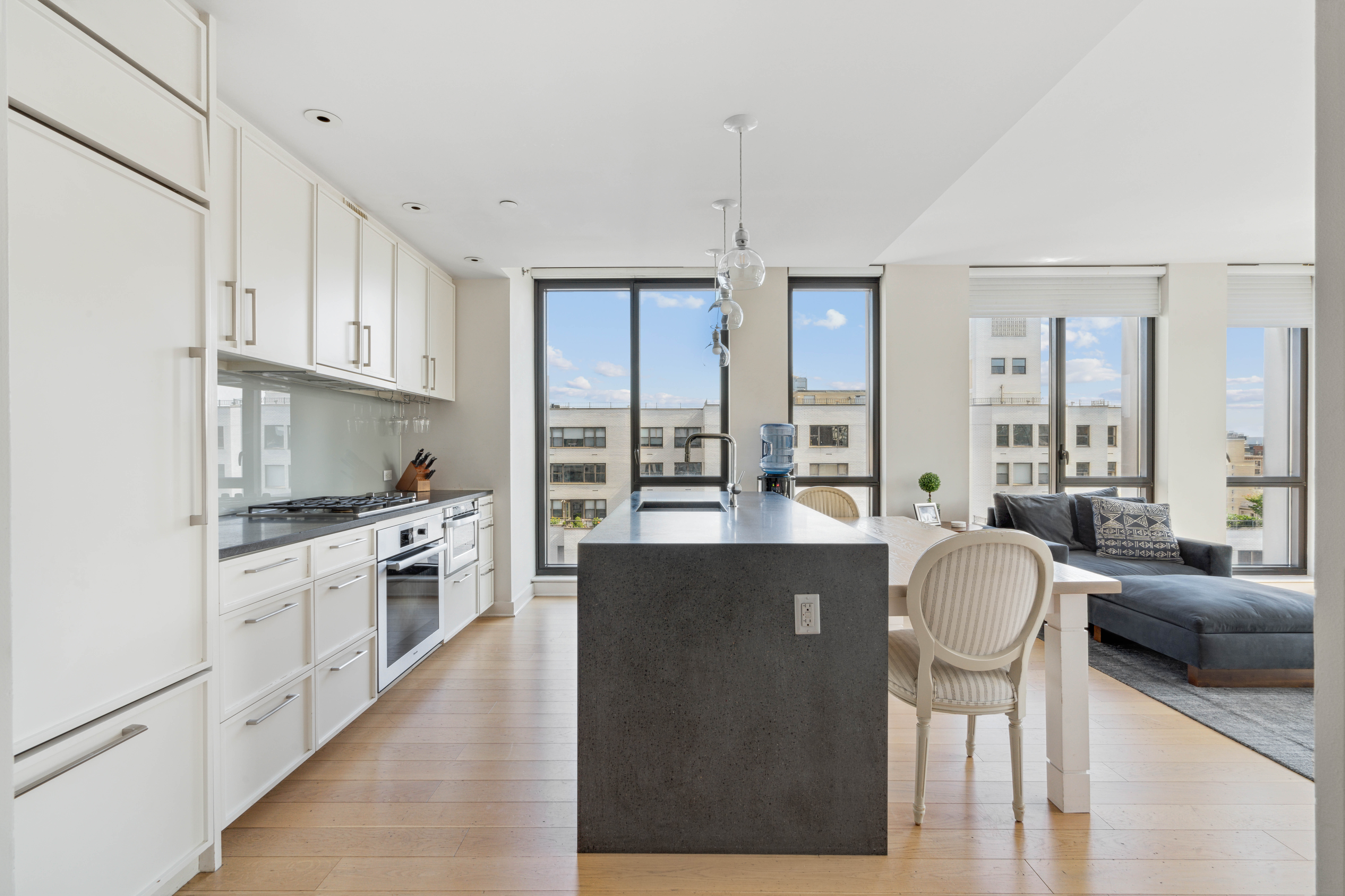160 East 22nd Street, Unit 18C Manhattan, NY 10010 - Photo 4 of 12 a kitchen with stainless steel appliances granite countertop a stove top oven a sink dishwasher a dining table and chairs with wooden floor