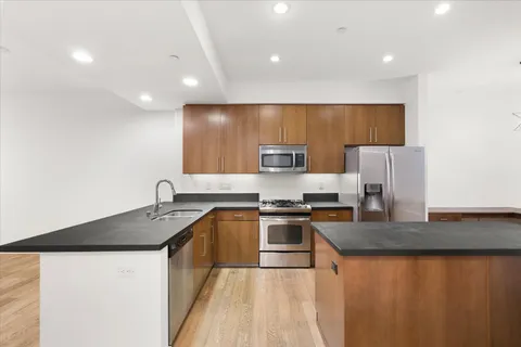a kitchen with stainless steel appliances granite countertop a sink a stove top oven a counter space and cabinets