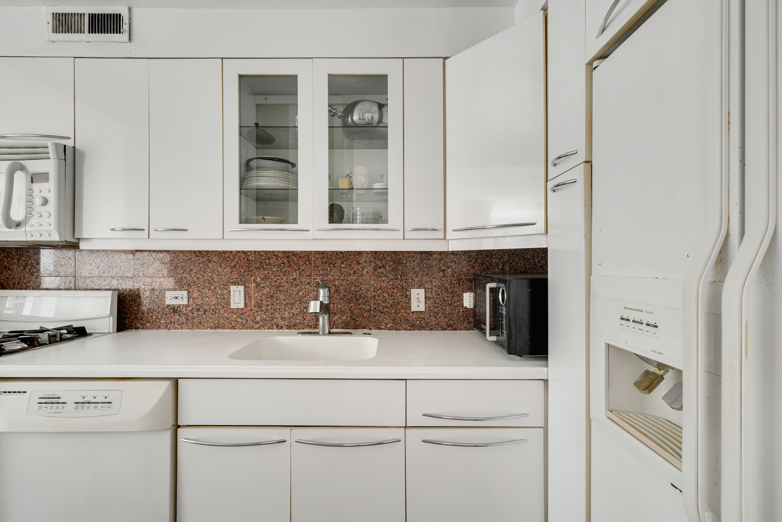 357 East 57th Street, Unit 5D Manhattan, NY 10022 - Photo 8 of 23 a kitchen with white cabinets and white appliances