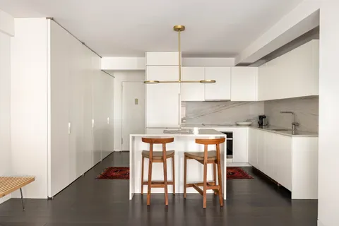a kitchen with stainless steel appliances wooden floors and white cabinets