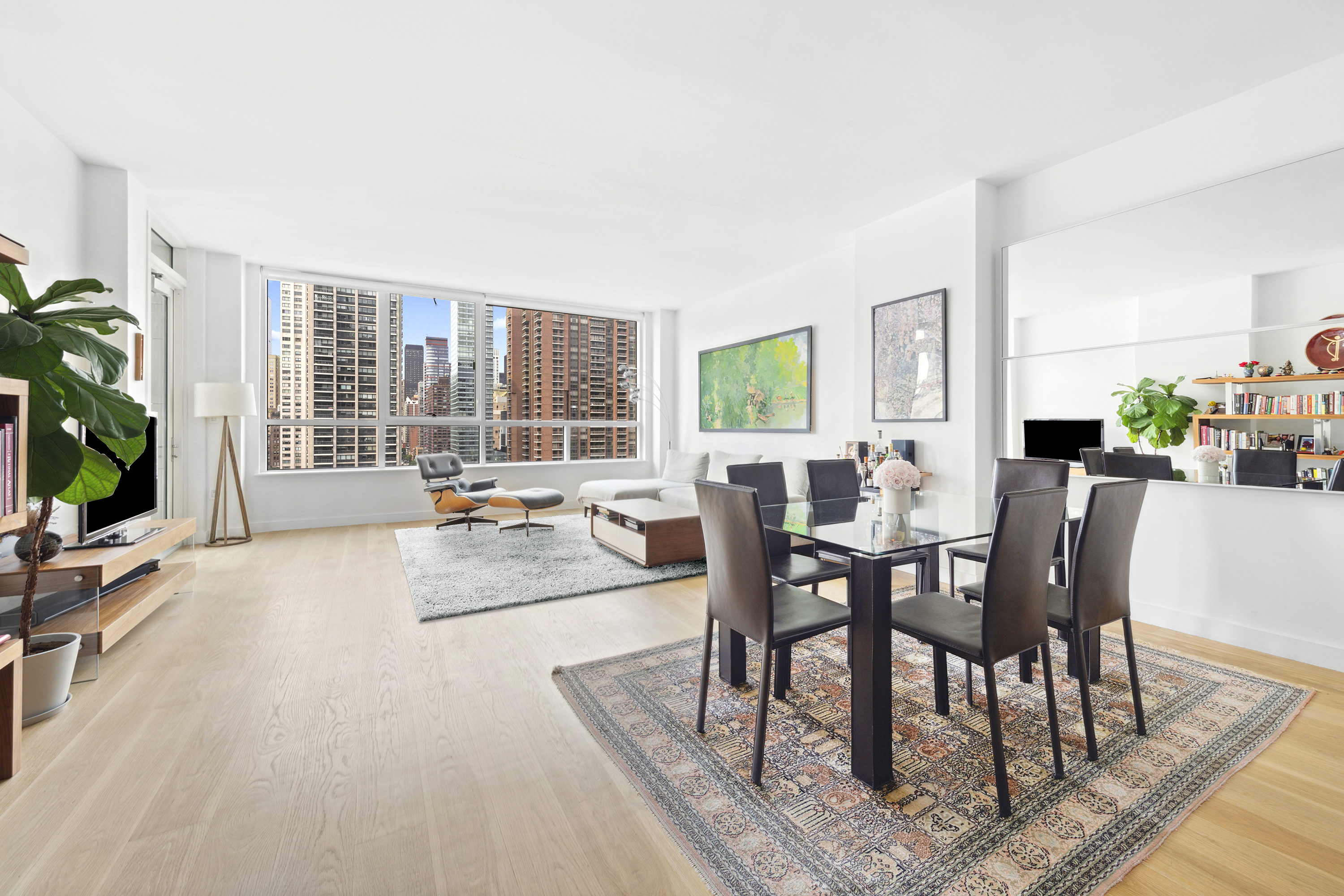 301 East 61st Street, Unit 12B Manhattan, NY 10065 - Photo 2 of 10 a view of a dining room with furniture a potted plant and wooden floor