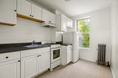a kitchen with white cabinets and window