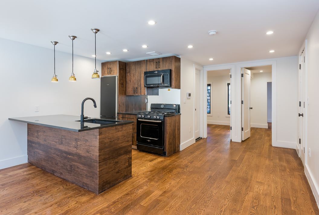 237 Macon Street, Unit 1 Brooklyn, NY 11216 - Photo 3 of 9 a kitchen with stainless steel appliances granite countertop a stove a sink a refrigerator and white cabinets with wooden floor