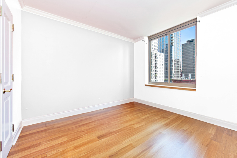 400 East 90th Street, Unit 7E Manhattan, NY 10128 - Photo 5 of 12 a view of an empty room with wooden floor and a window