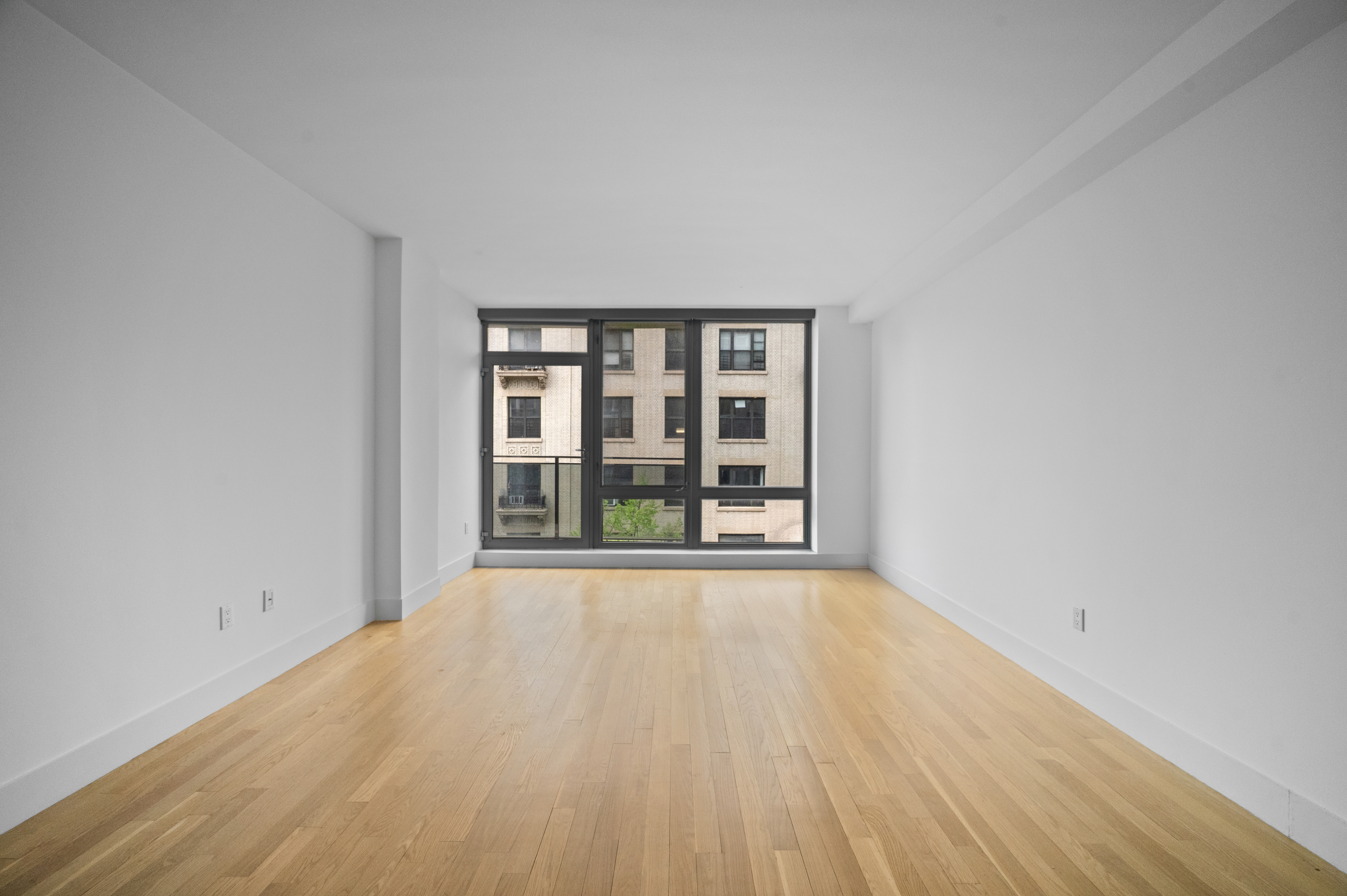 117 West 123rd Street, Unit 5D Manhattan, NY 10027 - Photo 2 of 18 an empty room with wooden floor and windows