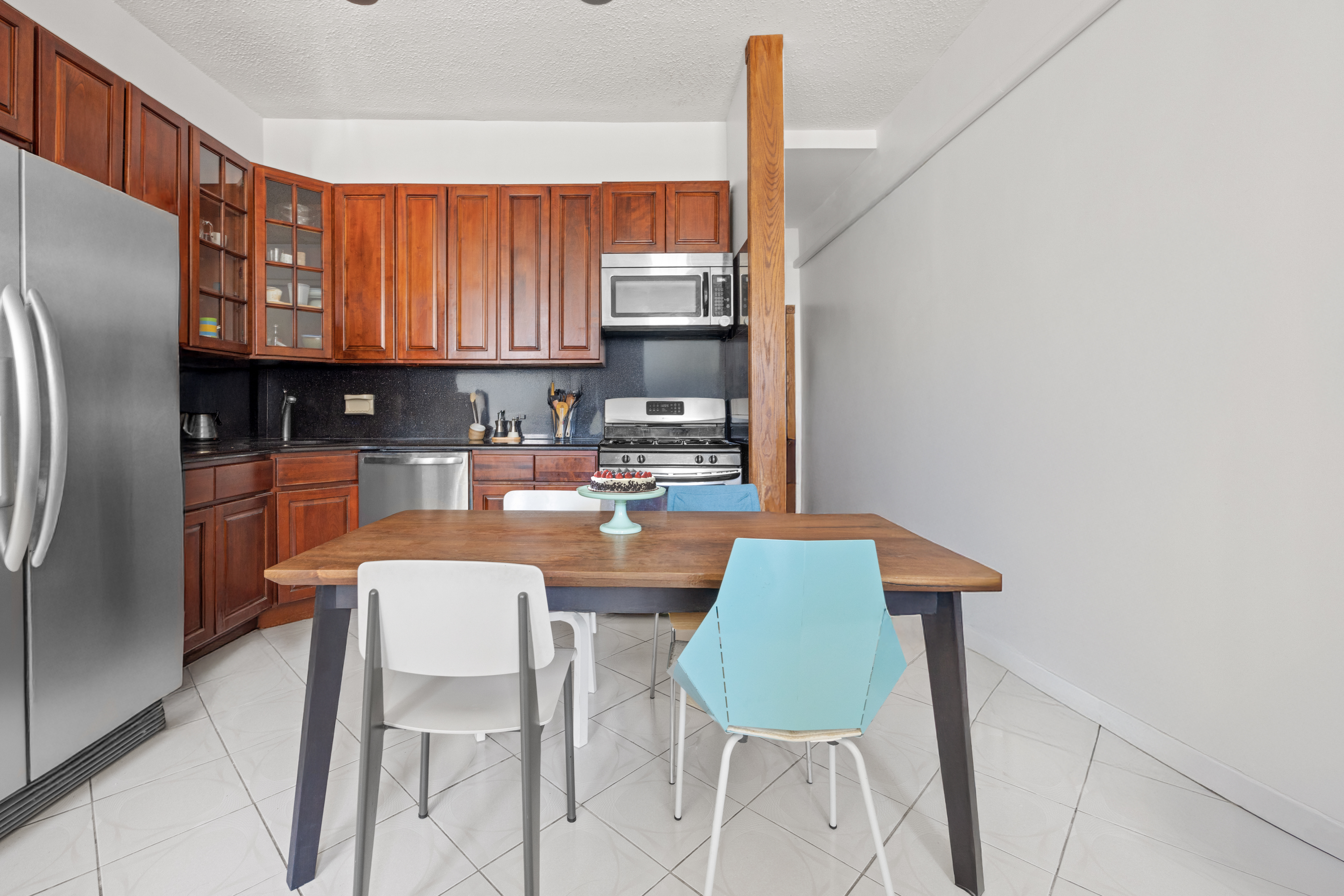 219 16th Street, Unit 1 Brooklyn, NY 11215 - Photo 3 of 7 a kitchen with stainless steel appliances a dining table chairs and a refrigerator