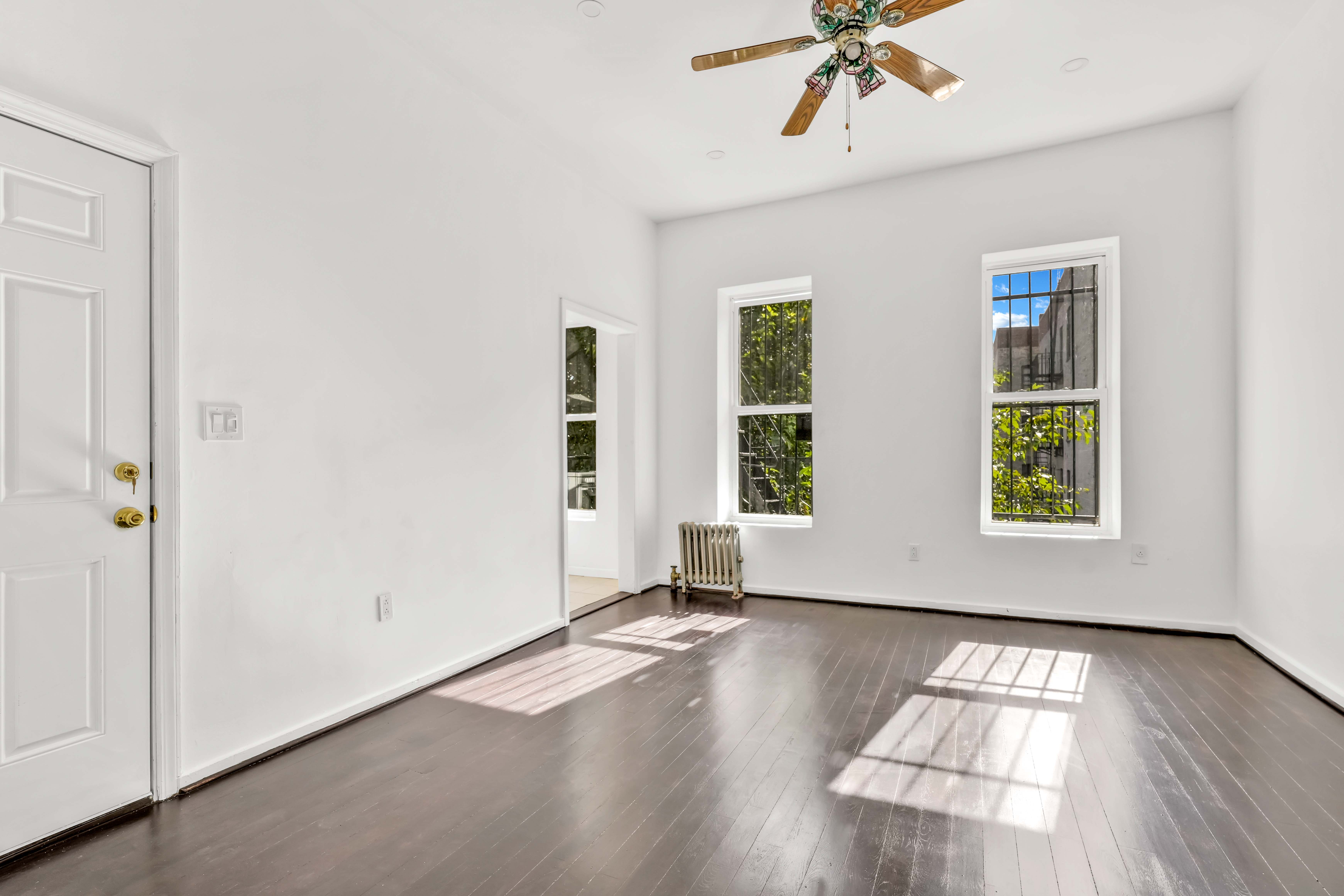 238 Vernon Avenue, Unit 2 Brooklyn, NY 11206 - Photo 8 of 21 an empty room with wooden floor chandelier fan and windows