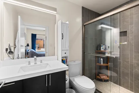 a bathroom with a sink a toilet a mirror and shower