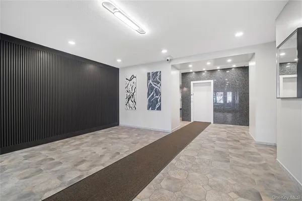 a view of an empty room with wooden floor and a kitchen
