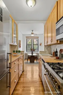 a kitchen with stainless steel appliances granite countertop a stove a sink dishwasher and white cabinets with wooden floor