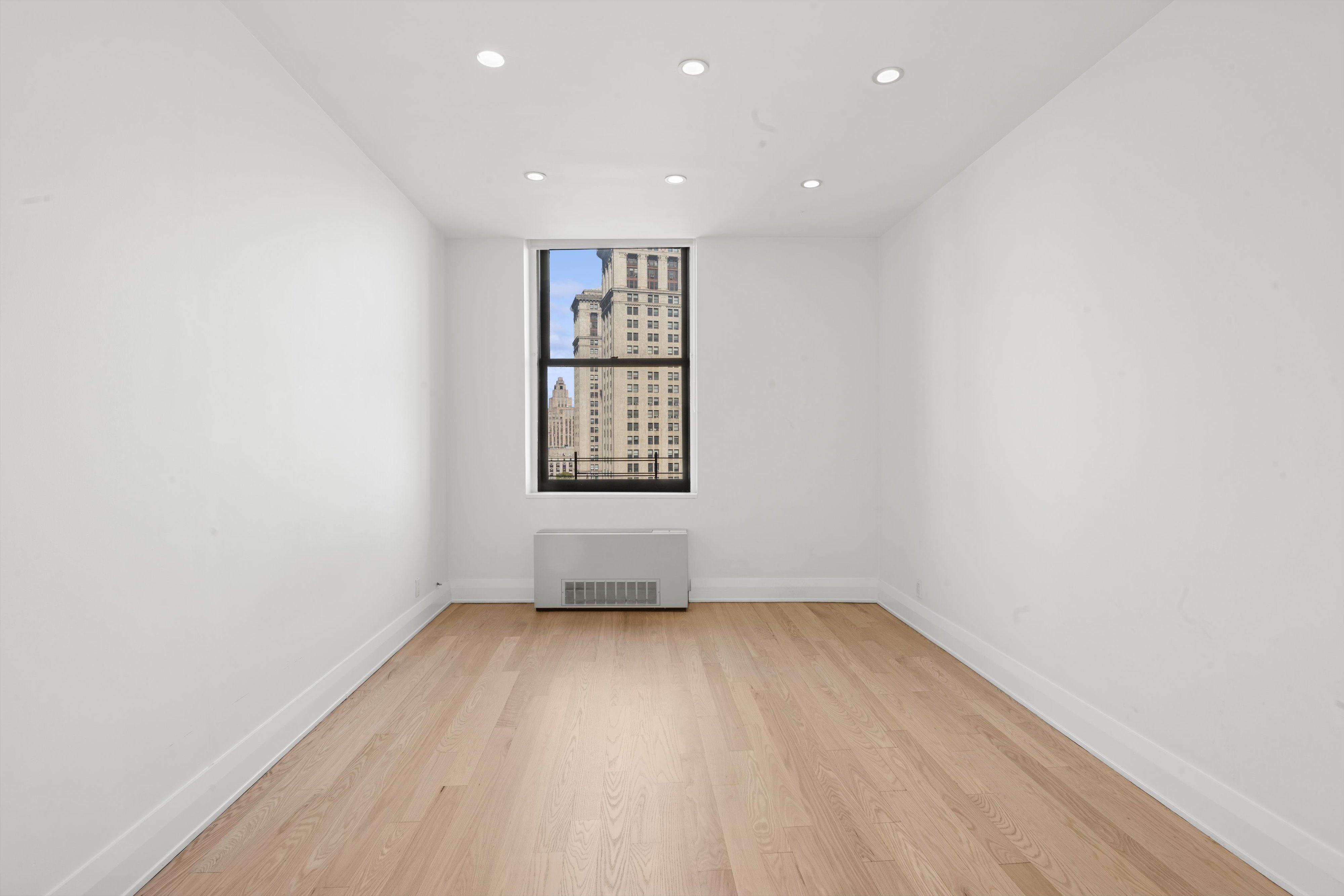 150 Nassau Street, Unit 11B Manhattan, NY 10038 - Photo 8 of 17 an empty room with wooden floor and windows