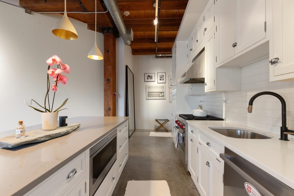 35 Channel Center Street, Unit 402 Boston, MA 02210 - Photo 7 of 35 a kitchen with kitchen island a sink appliances cabinets and a counter top space