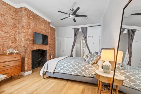a bedroom with a bed a fireplace and a flat tv screen on dresser