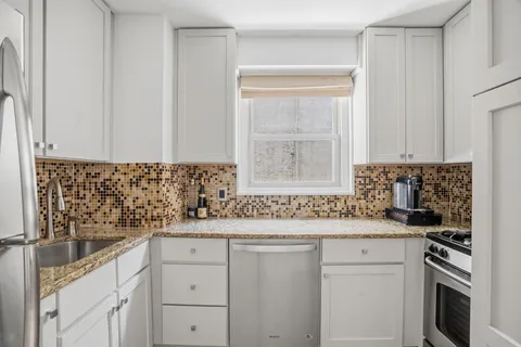 a kitchen with granite countertop white cabinets and white appliances