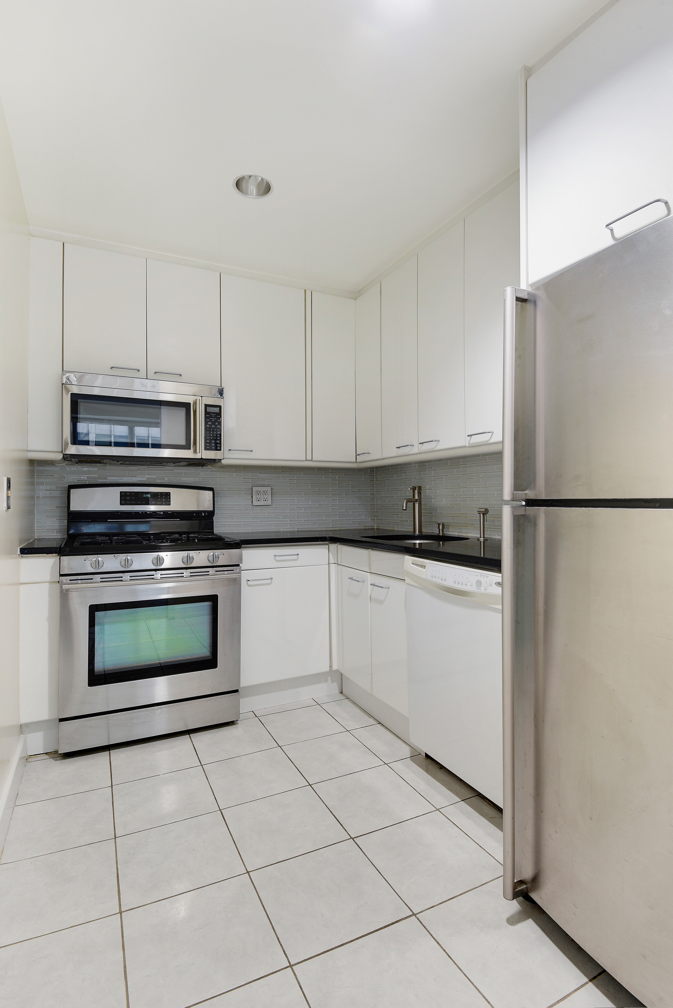 146 West 57th Street, Unit 38E Manhattan, NY 10019 - Photo 5 of 16 a kitchen with cabinets and steel stainless steel appliances