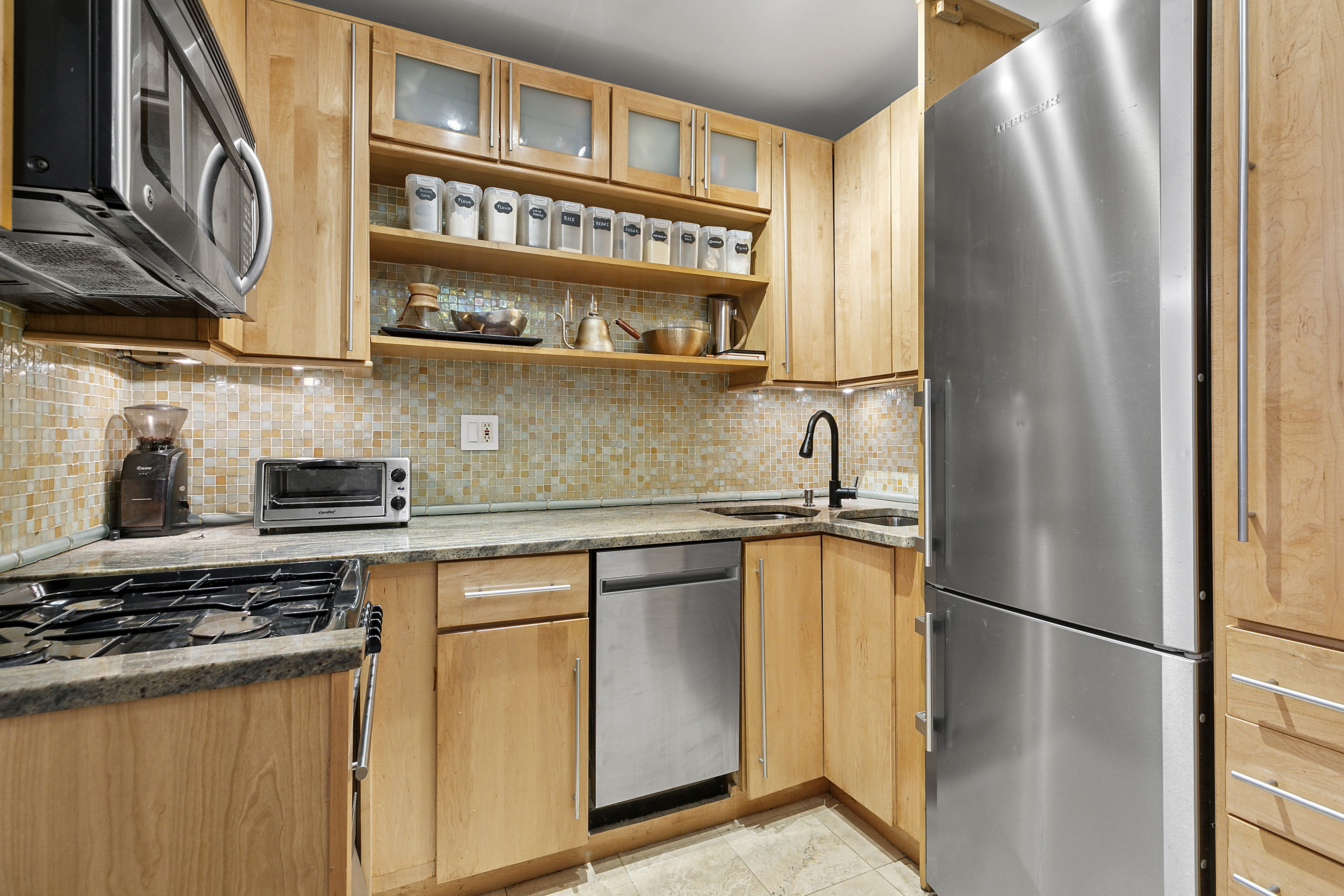 77 Bleecker Street, Unit 214 Manhattan, NY 10012 - Photo 4 of 5 a kitchen with stainless steel appliances granite countertop a refrigerator and a stove