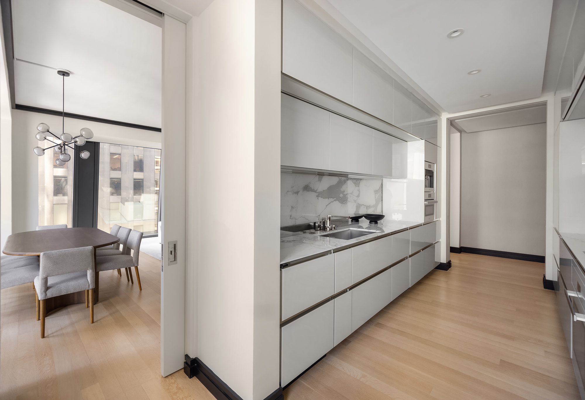 53 West 53rd Street, Unit 23D Manhattan, NY 10019 - Photo 6 of 11 a large white kitchen with stainless steel appliances granite countertop a stove and a refrigerator