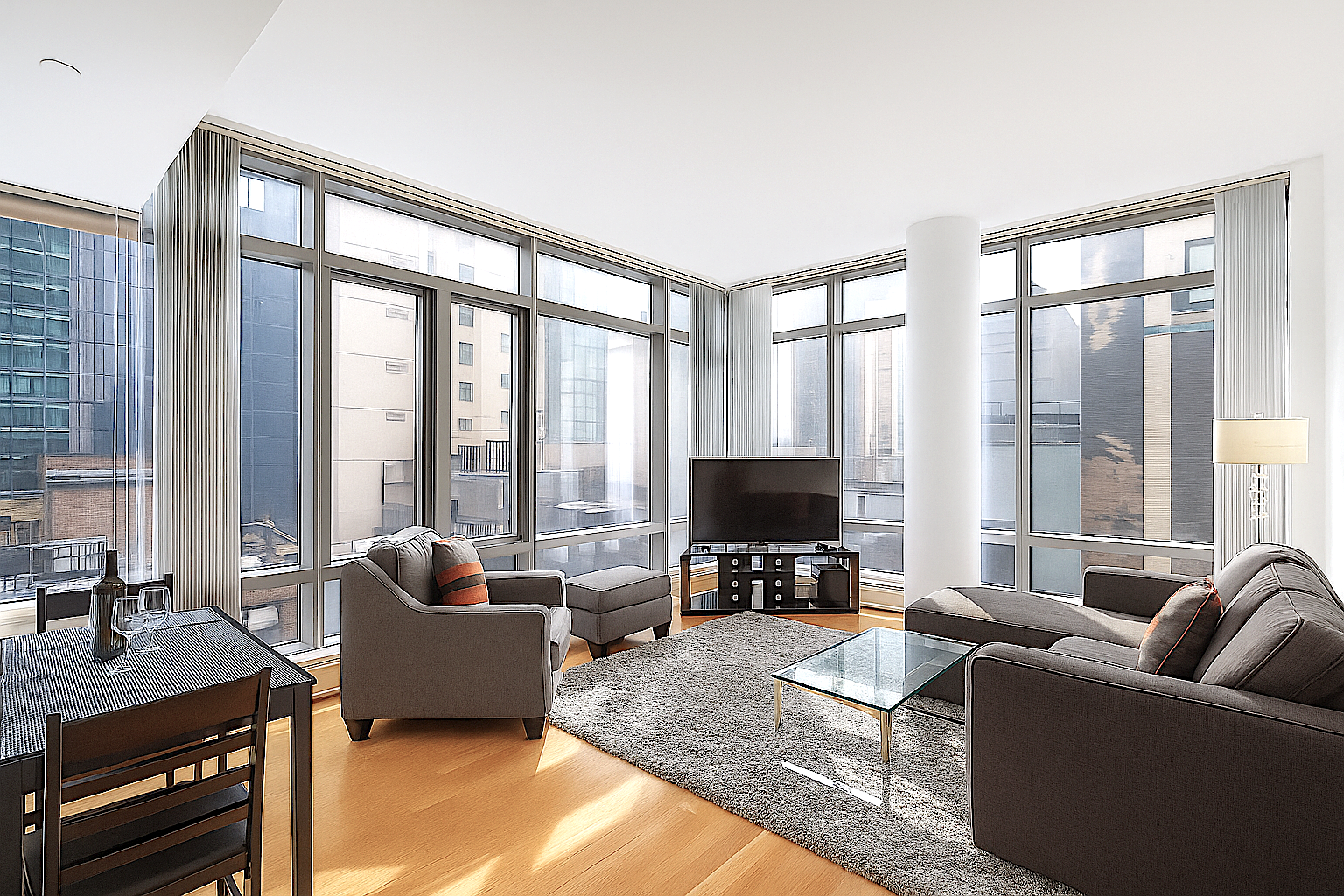 18 West 48th Street, Unit 17C Manhattan, NY 10036 - Photo 1 of 5 a living room with furniture a flat screen tv and a floor to ceiling window
