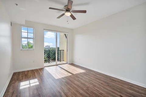 an empty room with wooden floor fan and windows