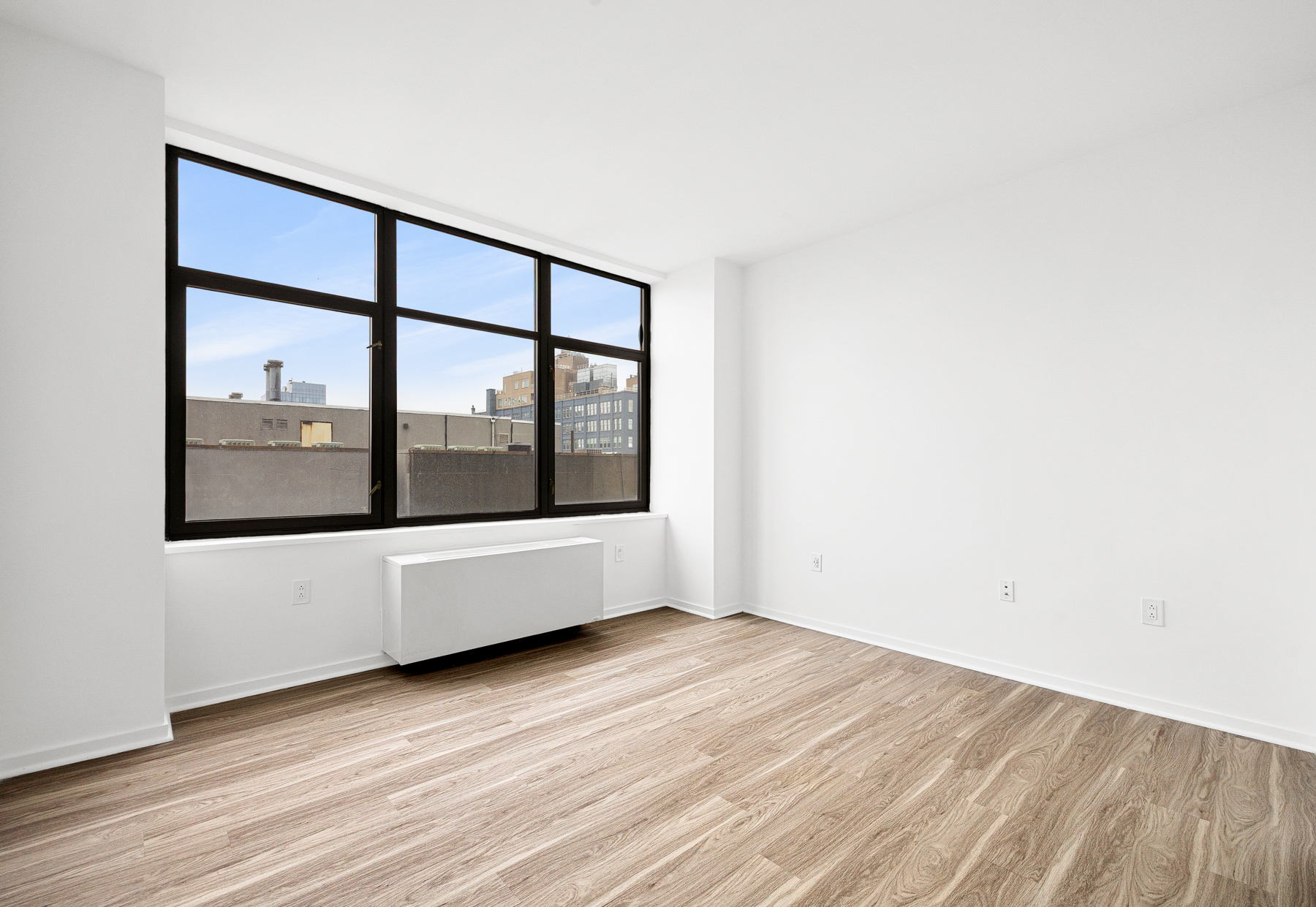 424 Bedford Avenue, Unit 6B Brooklyn, NY 11249 - Photo 7 of 11 a view of an empty room with wooden floor and a window