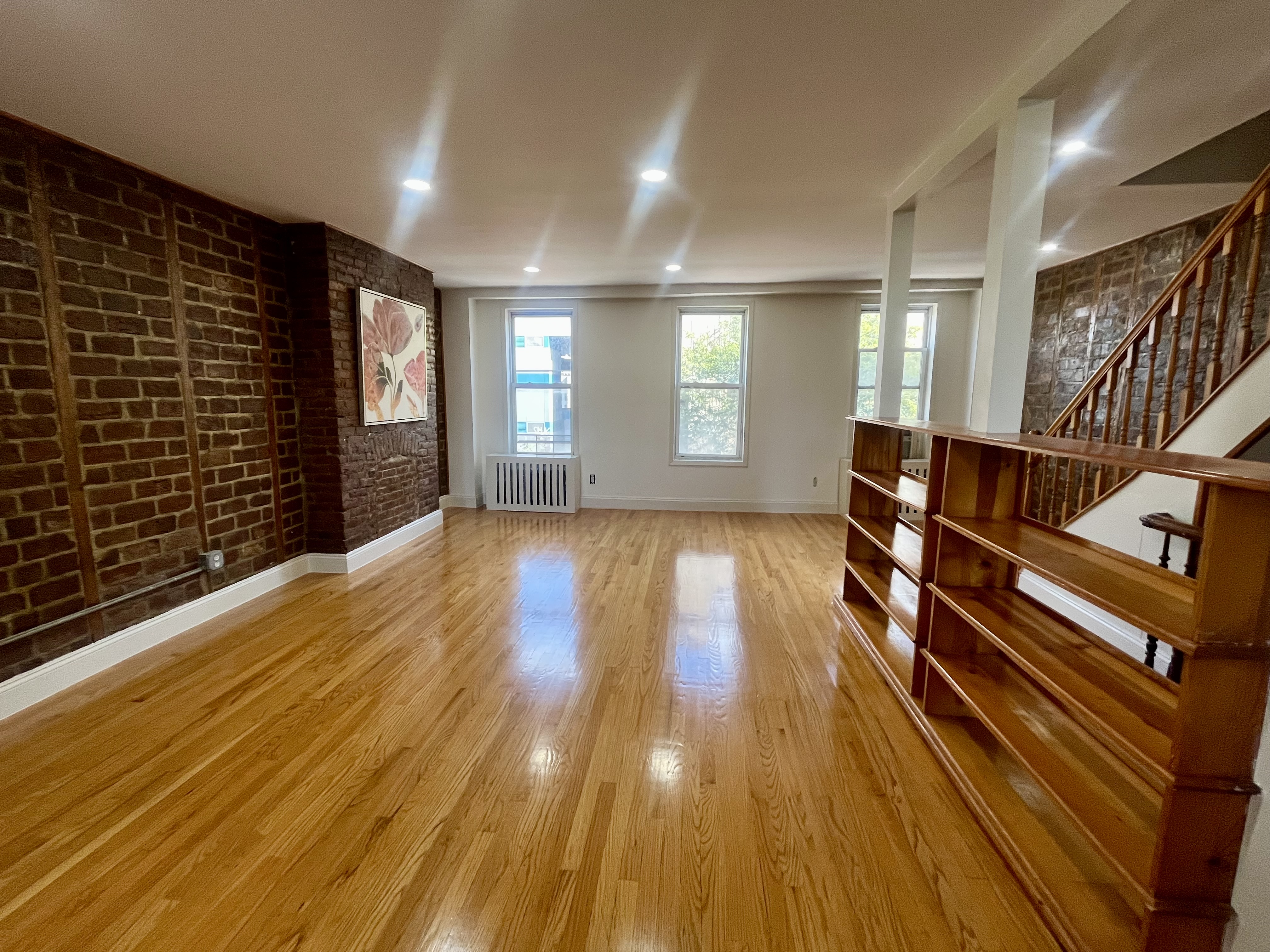 a view of an empty room with wooden floor and windows