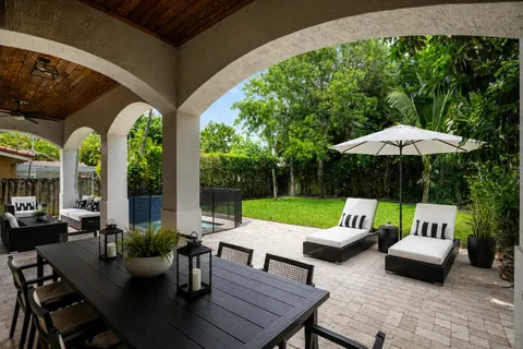a view of patio with table and chairs under an umbrella with a small yard