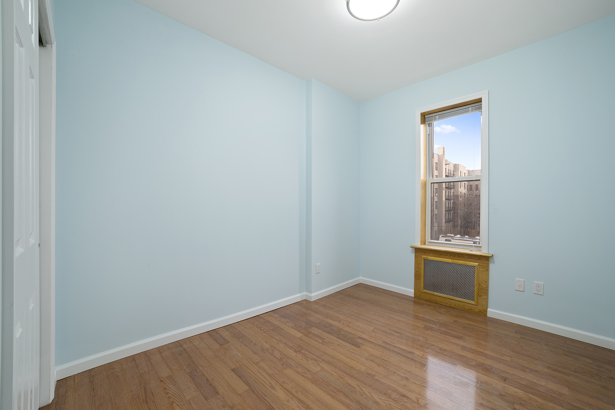 208 Lenox Road, Unit 3 Brooklyn, NY 11226 - Photo 4 of 7 a view of an empty room with wooden floor and a window