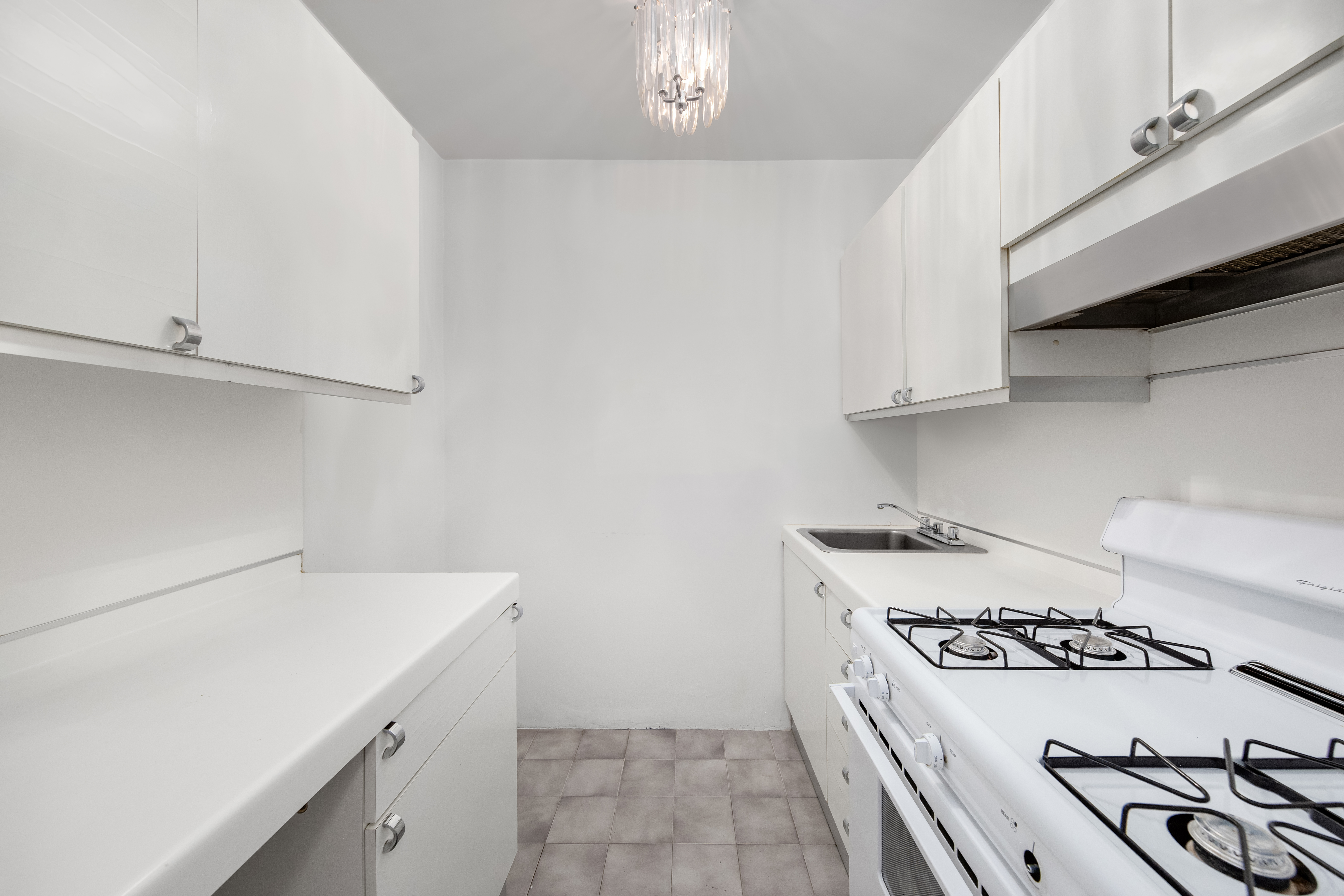 77 West 55th Street, Unit 16A Manhattan, NY 10019 - Photo 3 of 6 a kitchen with a stove and white cabinets
