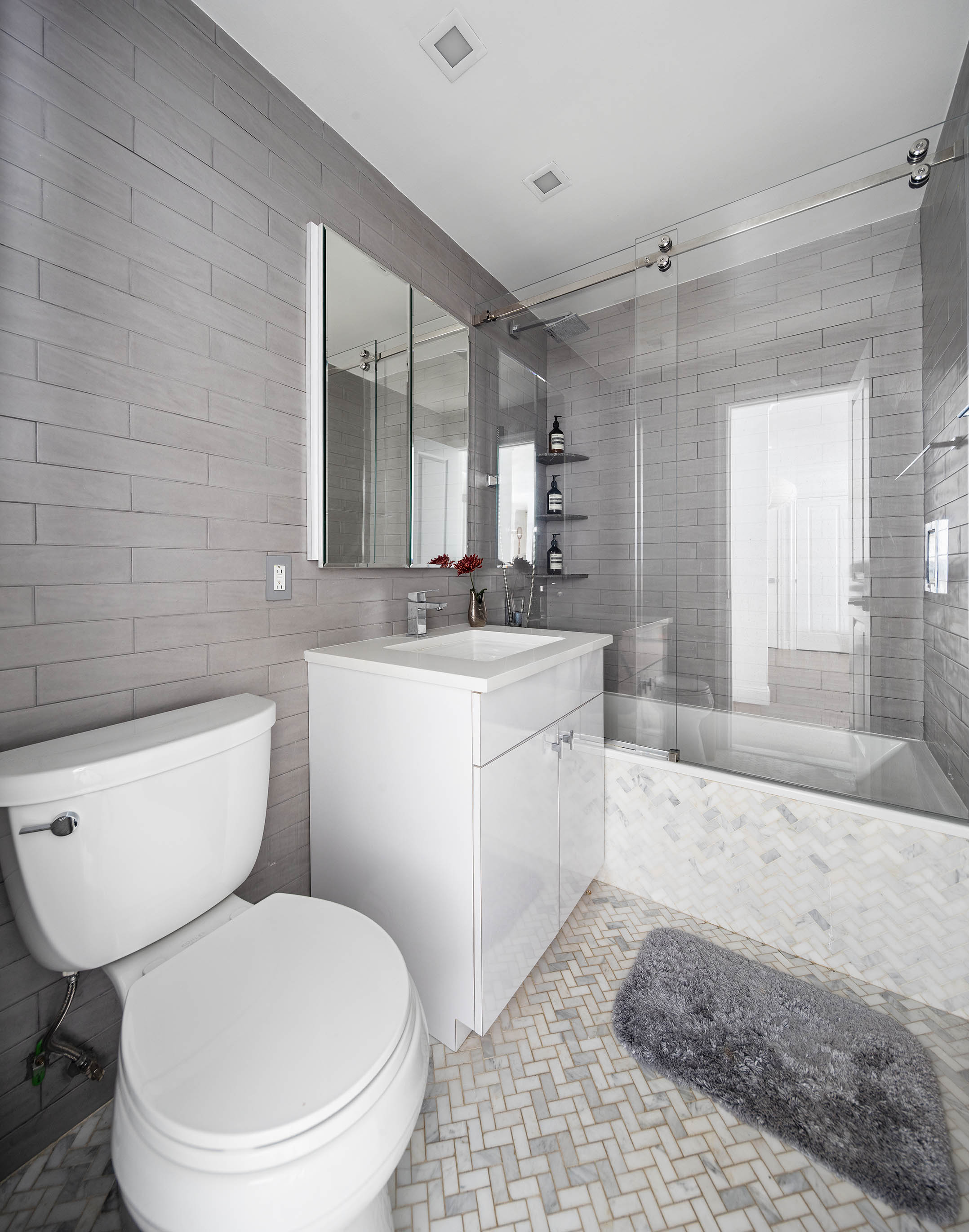 301 East 69th Street, Unit 7E Manhattan, NY 10021 - Photo 6 of 15 a bathroom with a granite countertop toilet a sink a mirror and shower