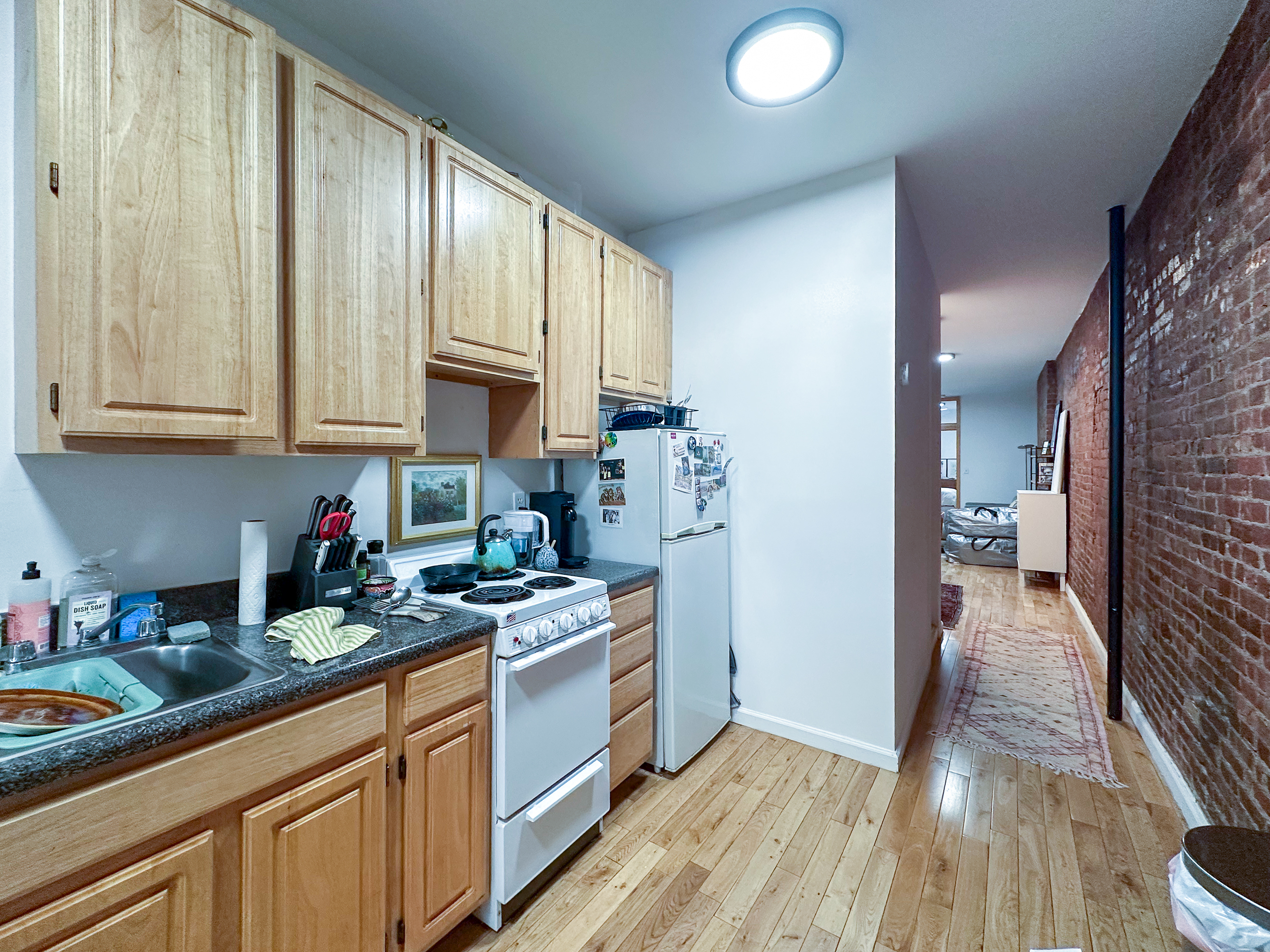 215 East 5th Street, Unit 7 Manhattan, NY 10003 - Photo 8 of 15 a kitchen with stainless steel appliances granite countertop a stove a sink dishwasher and a refrigerator with wooden floor