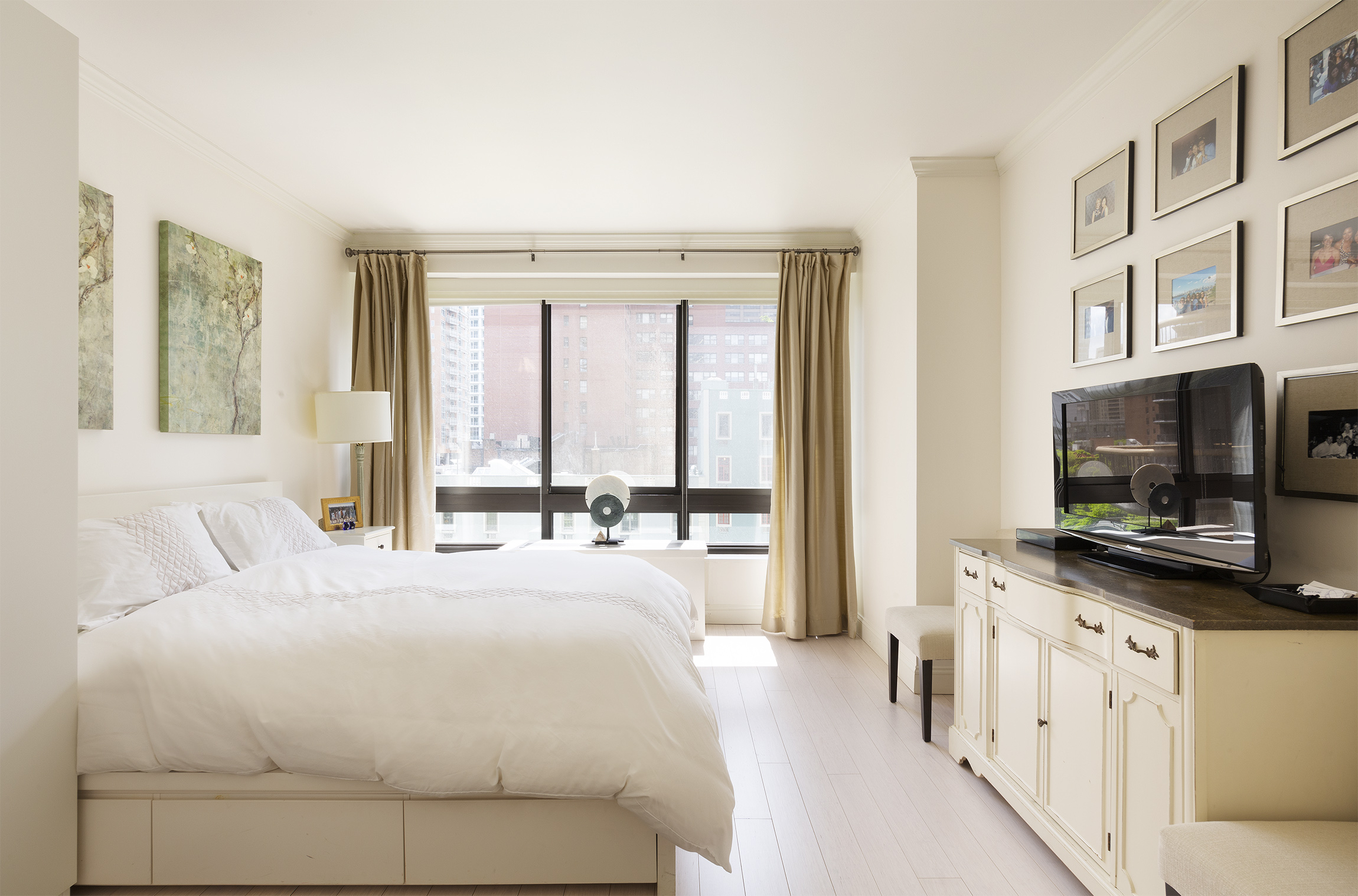 167 East 61st Street, Unit 7C Manhattan, NY 10065 - Photo 3 of 7 a large bedroom with a large window and a flat screen tv