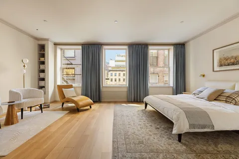 a bedroom with a bed and large windows