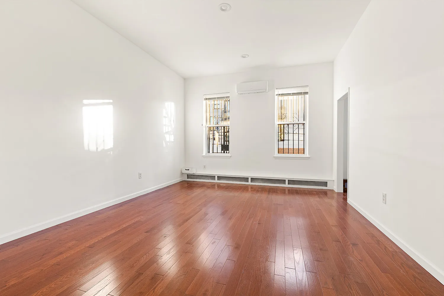 an empty room with wooden floor and windows