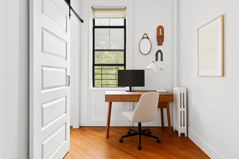 a view of a workspace with furniture and a window