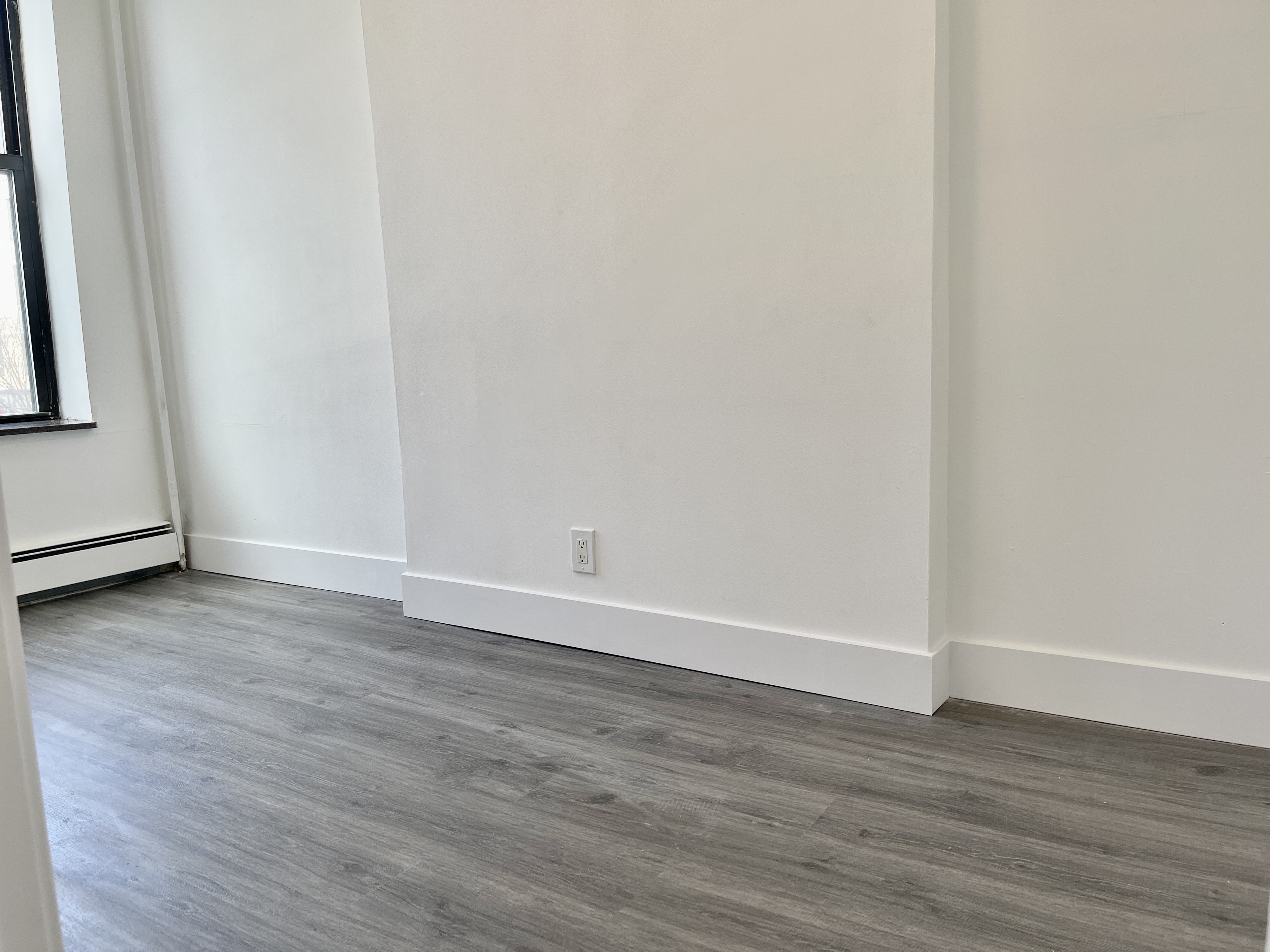 1999 3rd Avenue, Unit 1 Manhattan, NY 10029 - Photo 5 of 23 a view of an empty room with wooden floor and a window