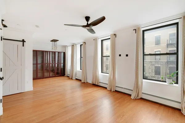 an empty room with wooden floor cabinet and windows