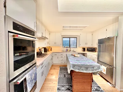 a large kitchen with stainless steel appliances granite countertop a refrigerator and a stove