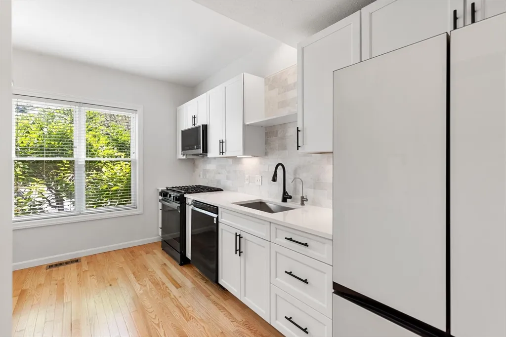 a kitchen with stainless steel appliances a sink cabinets and a window