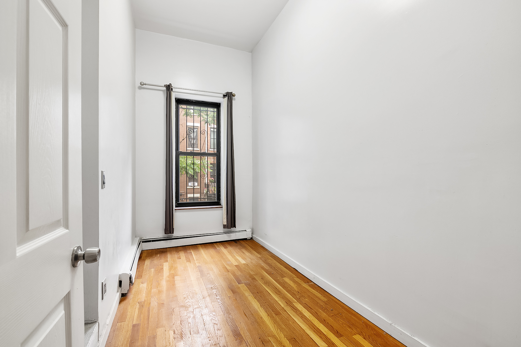 357 West 120th Street, Unit 1R Manhattan, NY 10027 - Photo 5 of 9 a view of an empty room with wooden floor and a window