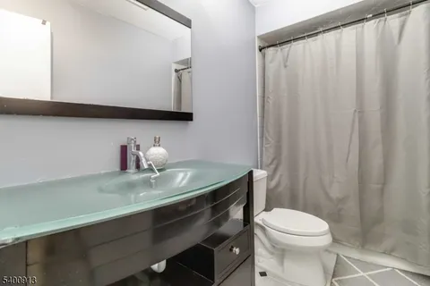 a bathroom with a granite countertop sink a toilet and a mirror