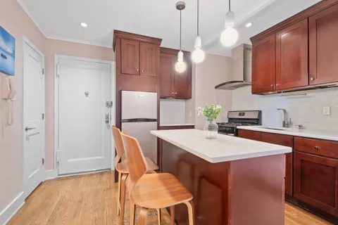 a kitchen with stainless steel appliances kitchen island granite countertop a table chairs and a refrigerator