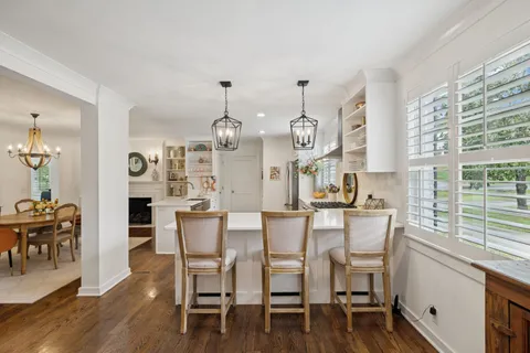 a kitchen with stainless steel appliances granite countertop a table chairs and a refrigerator