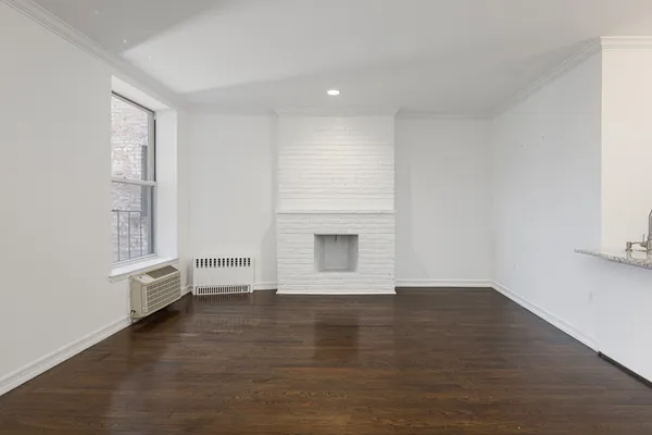 a view of an empty room with a window and wooden floor