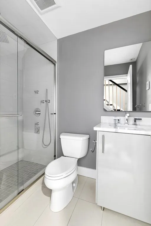 a bathroom with a toilet sink vanity granite and shower