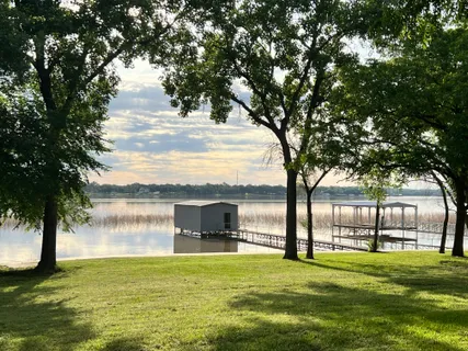 a view of a lake with a big yard and large trees